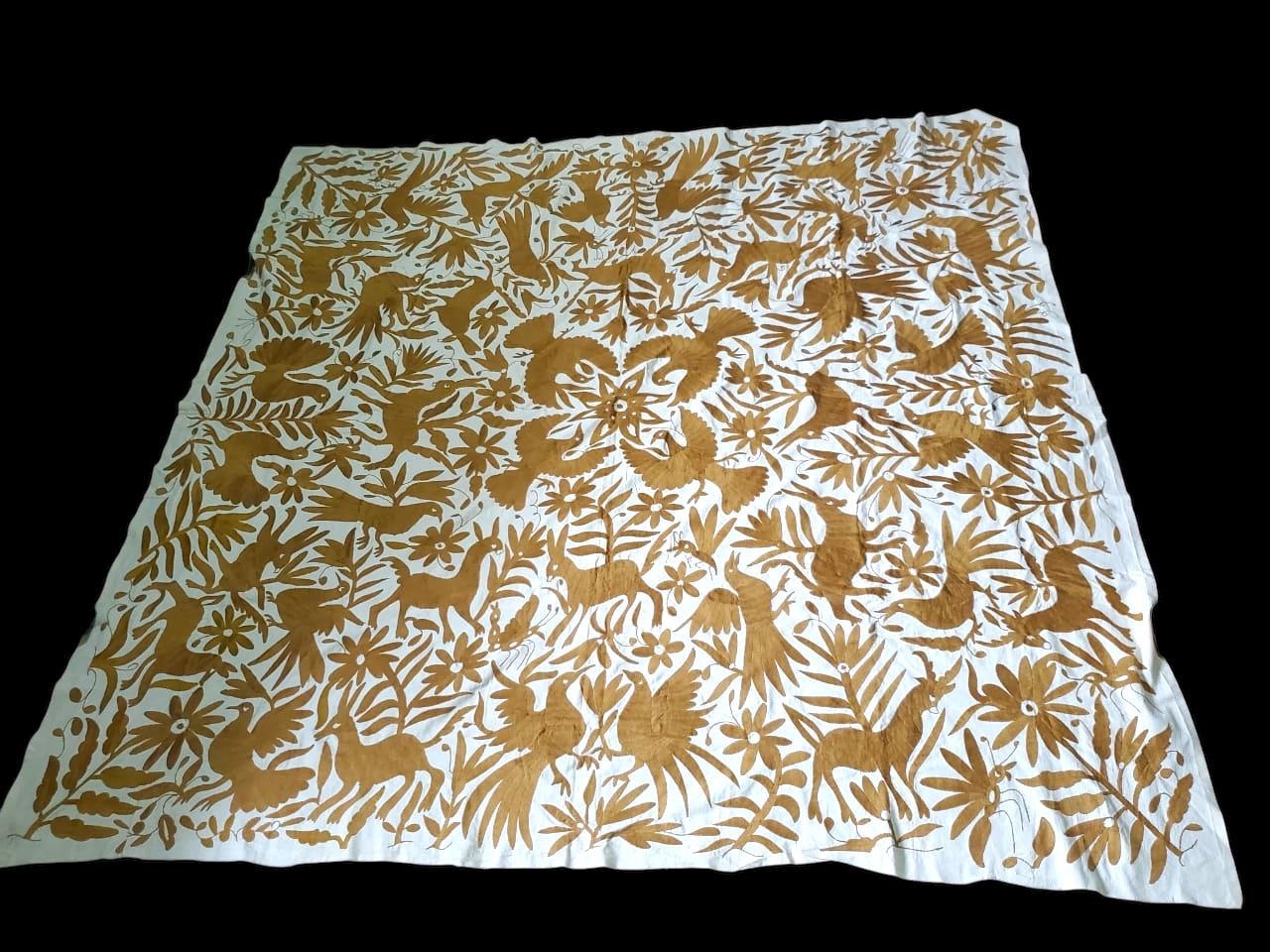 Extra large beige Otomi tapestry hand-embroidered with floral and animal patterns, laid flat.