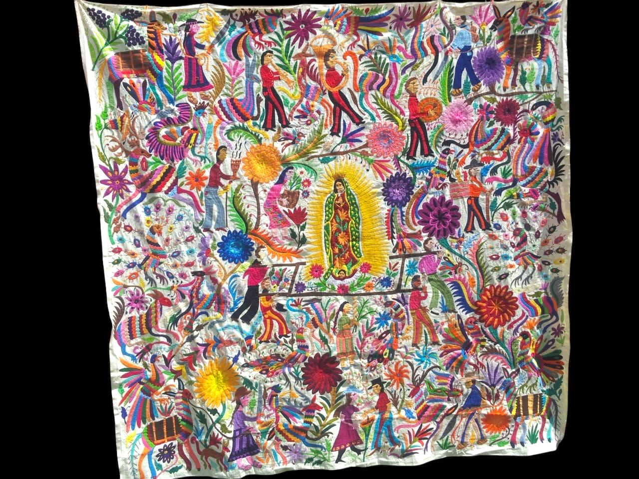 Extra large Otomi tapestry wall art hand-embroidered in Mexico, featuring a vibrant and colorful design with the Virgin Mary in the center, surrounded by floral patterns and figures.