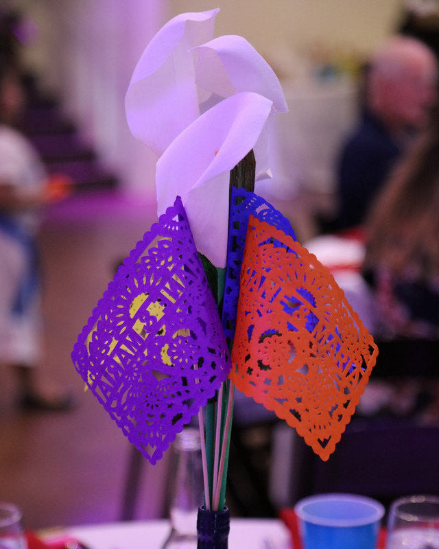Flowers and colorful paper flag favors in vase decorating wedding reception table.
