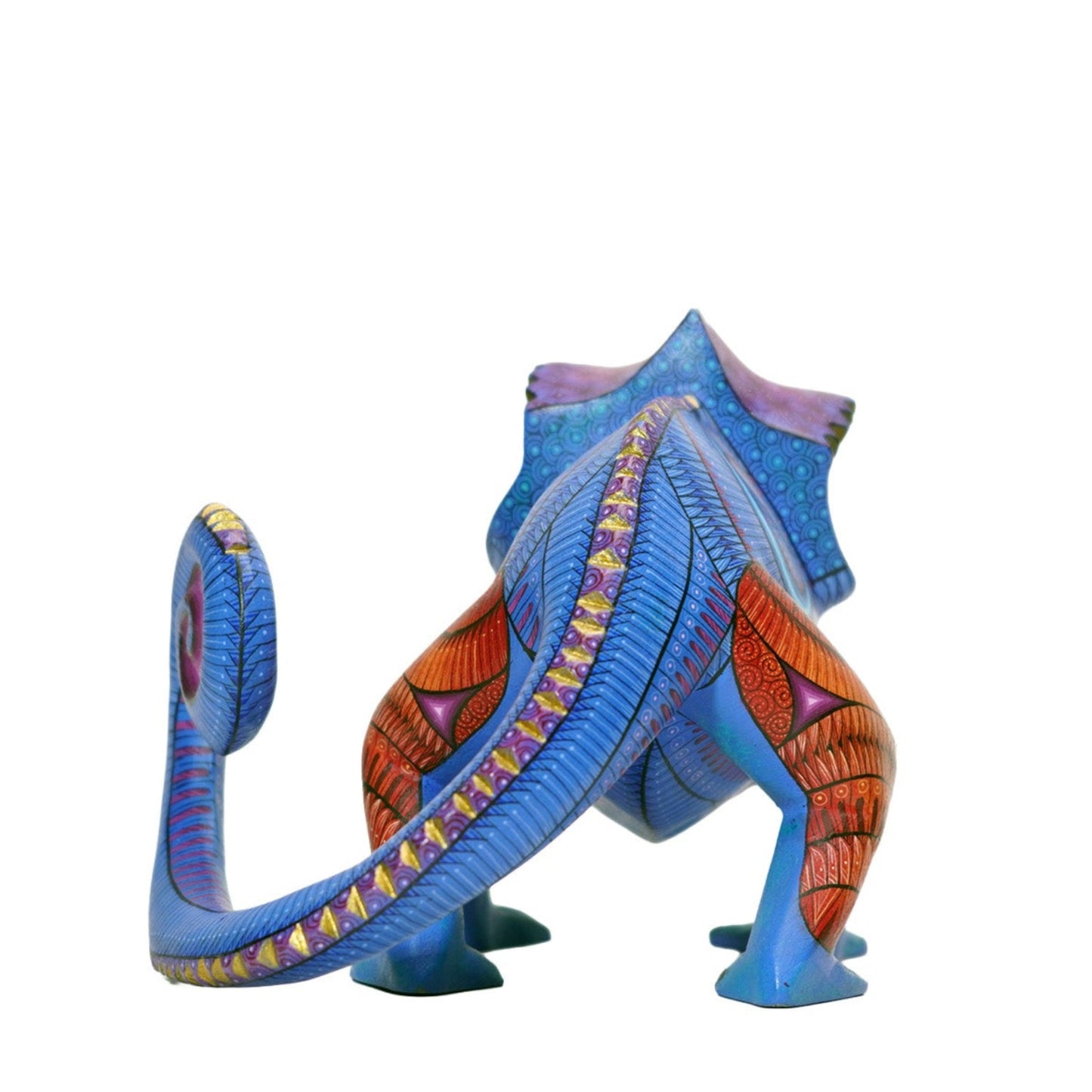 Back of a colorful wooden chamelion art figurine with detailed painted designs on a white background. 