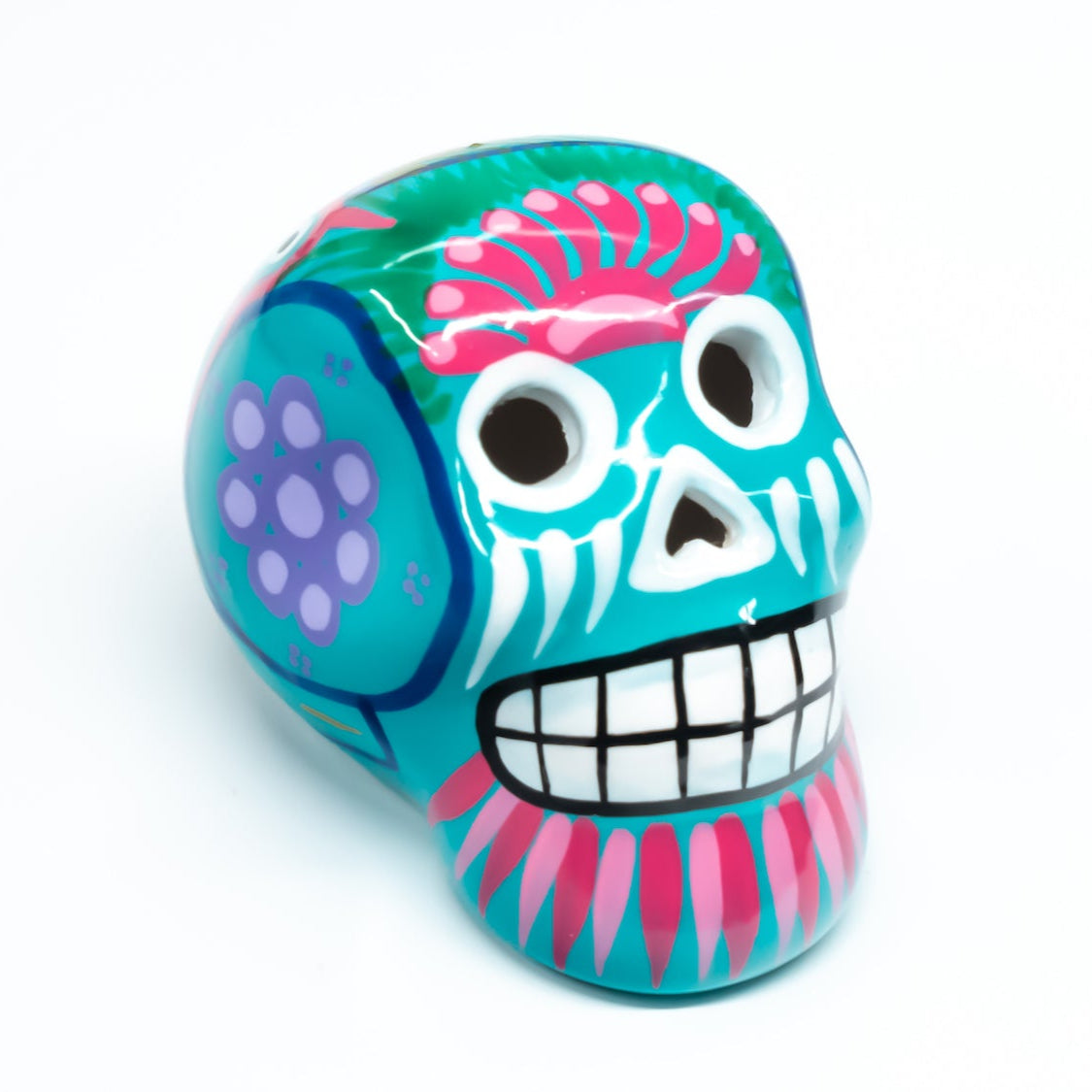 Colourful turquoise skull with hand-painted design, on a white background