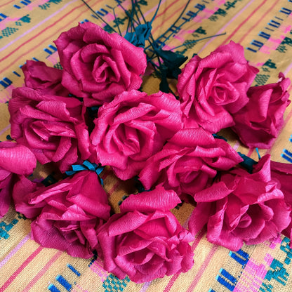 A group of red crepe paper roses arranged on a patterned surface.