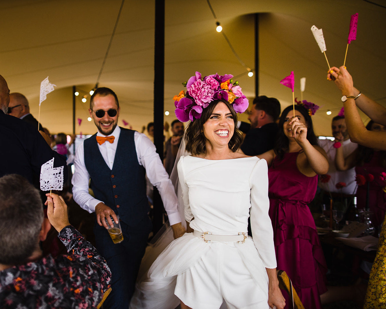 Bride and groom walking down an aisle with guests colorful flags.