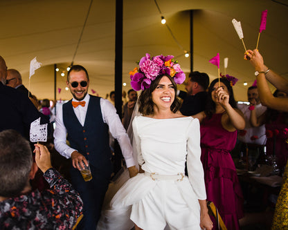 Bride and groom walking down an aisle with guests colorful flags.