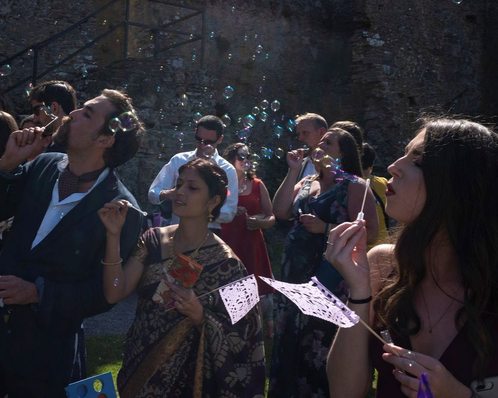 People blowing bubbles and waving flags at wedding in a castle