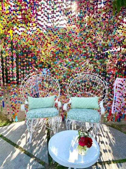 Pom pom photo background wall hanging decorations with two chairs and a table in the foreground.