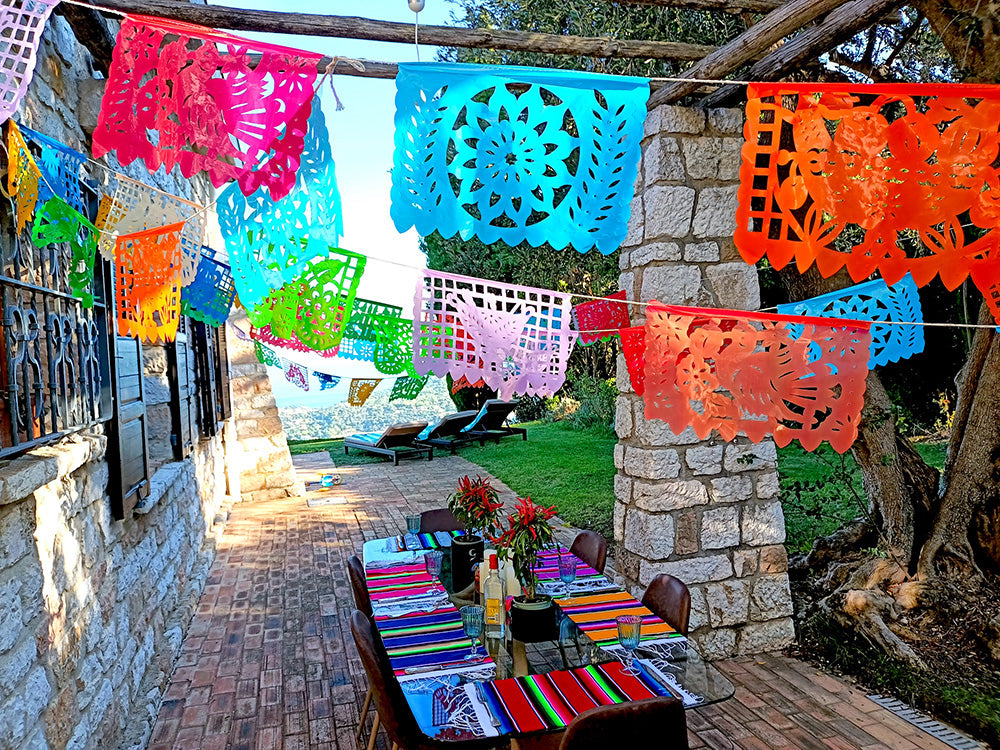 A colorful outdoor party decoration setup with a series of plastic flags in various colors hanging along a rope, displayed over a table set for an event.