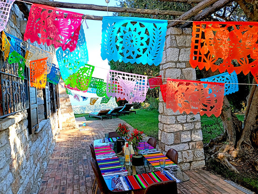 A colorful outdoor party decoration setup with a series of plastic flags in various colors hanging along a rope, displayed over a table set for an event.